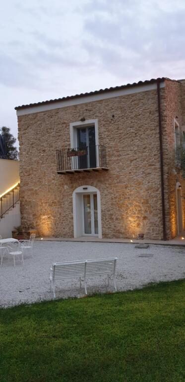 Stone façade of Uliwood lit at dusk with garden seating